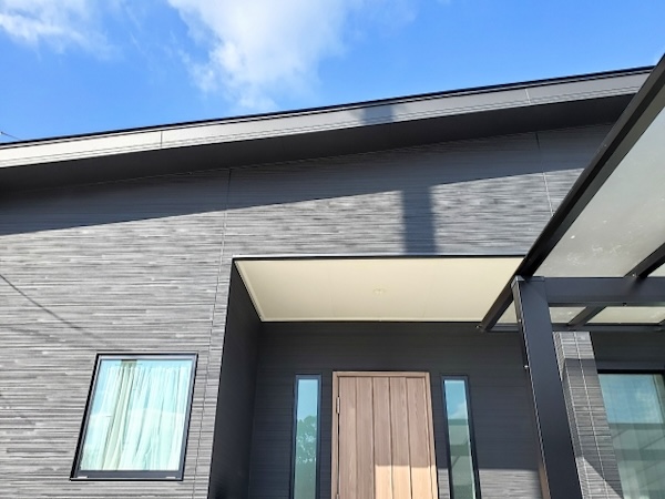 日差しを受けた住宅の外壁。素材の質感や色の見え方、窓枠や玄関ドアとの組み合わせがわかる外観の写真